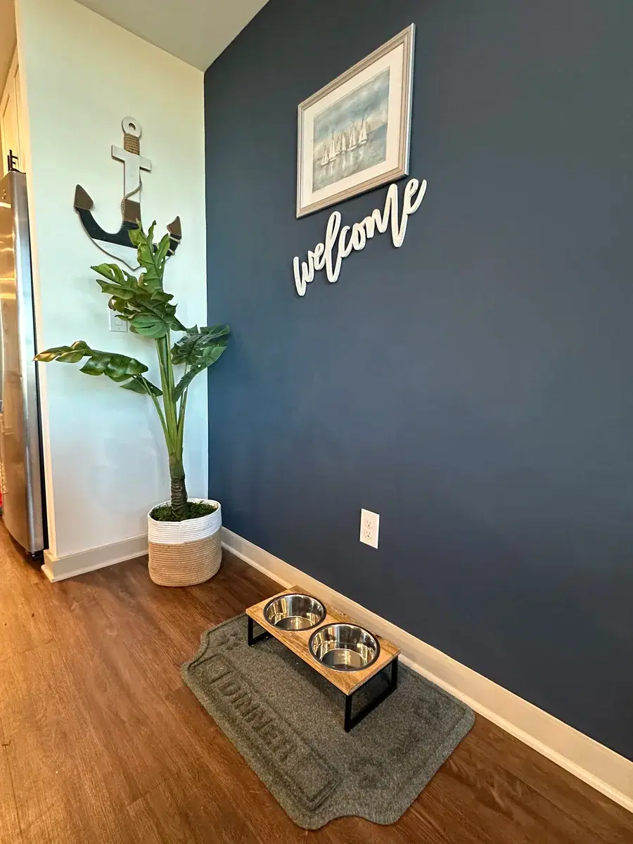 Pet feeding station with stainless dog bowls and welcome sign at Grandy Cove